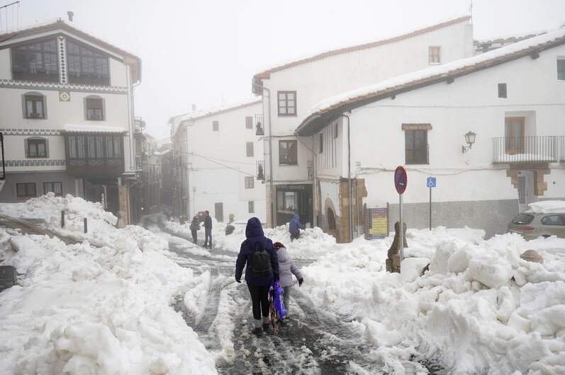 People walking in a snow covered village in Spain.