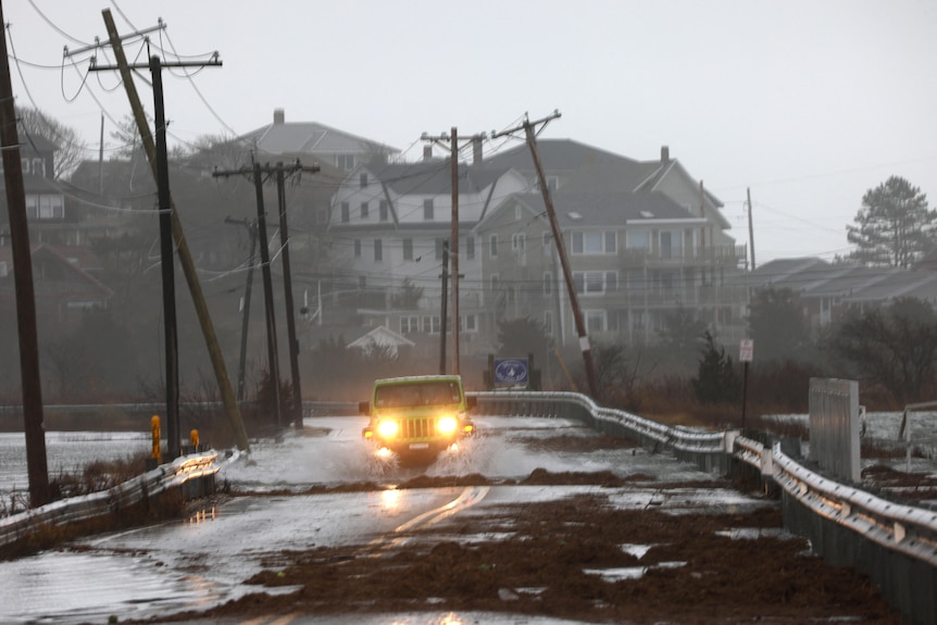 A car driving on a road with fallen power lines in the background