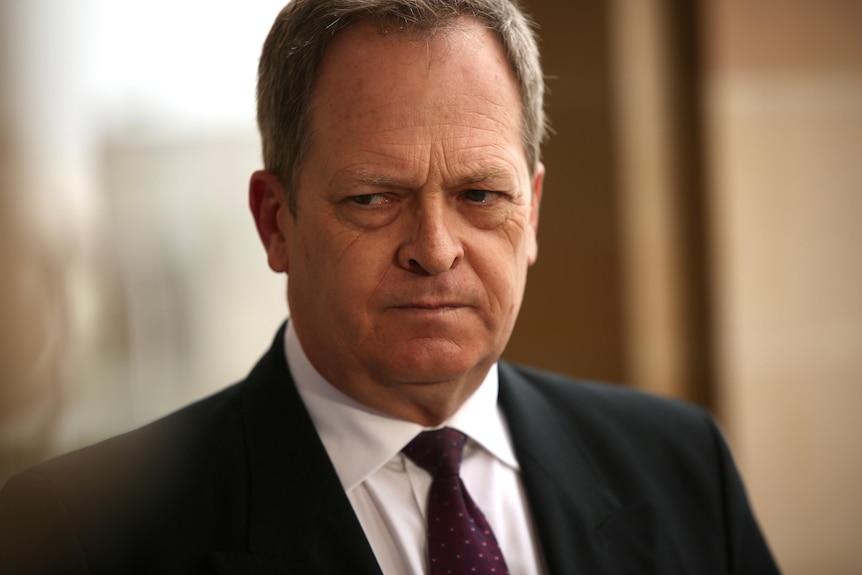 A man in a black suit speaks at a press conference