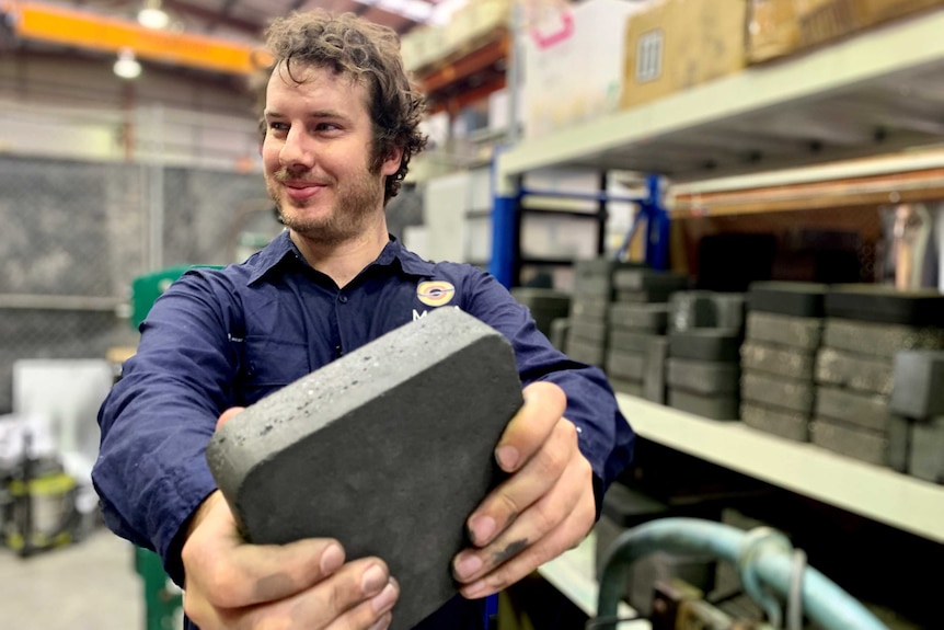 MGA Thermal's Alex Post holds one of its heat storing bricks in his hands in a workshop.