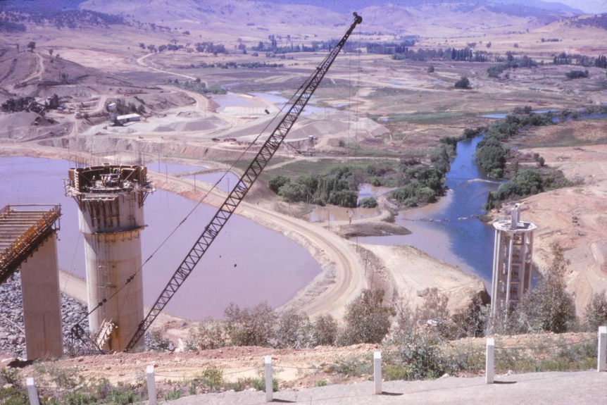 An historic photo looking down into a valley as construction cranes work at the edges.