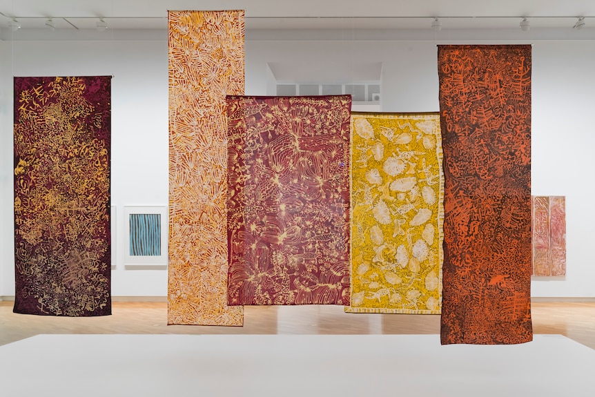 Large, earth coloured batiks by artist Emily Kam Kngwarray hang from the ceiling in the NGA