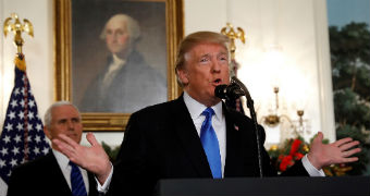 Donald Trump holds out his hands as he speaks into a microphone.