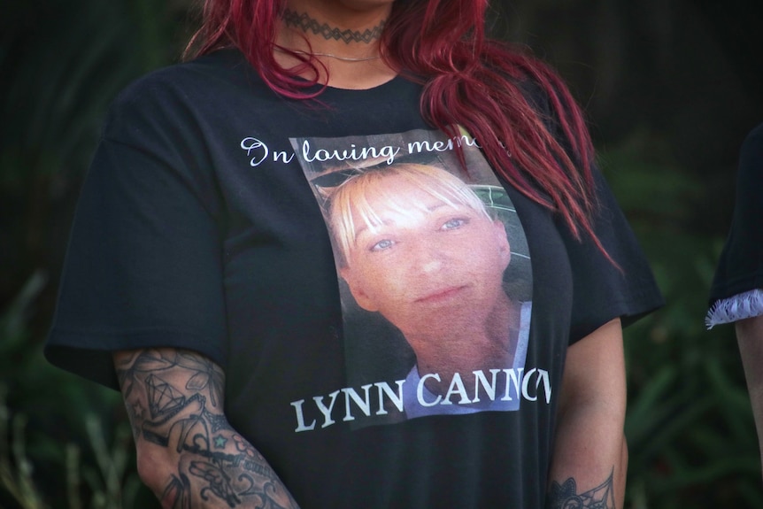 A close-up shot of a woman's black t-shirt with a picture of Lynn Cannon on it, and the words 'In loving memory, Lynn Cannon'.