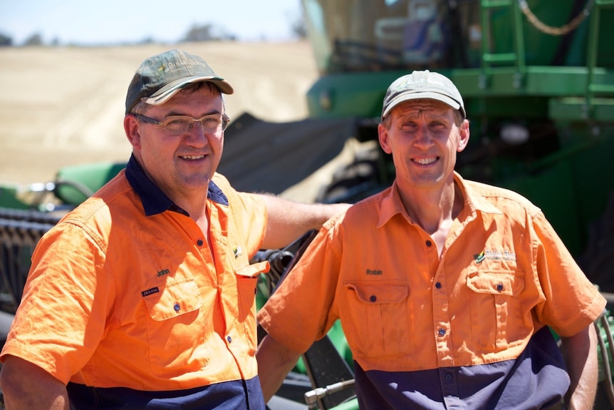 Two farmers in front of harvester at Bulla Burra Farms at Loxton, SA.