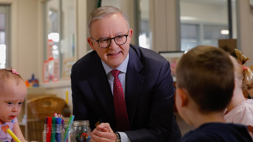 Anthony Albanese sits at a table talking with children in a child care class