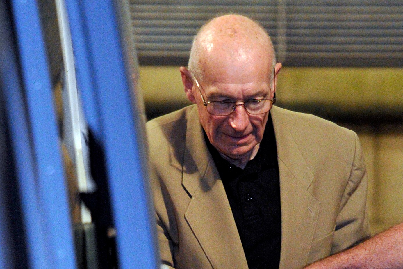 A man with a bold head and glasses