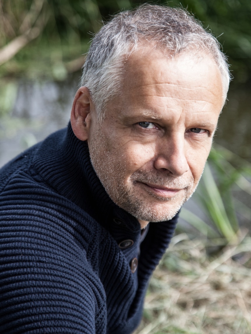 Cellist Pieter Wispelwey in nature smiling into the camera.