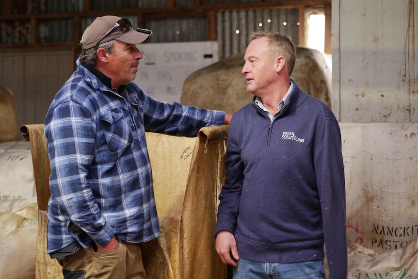 Farmer and wool broker talking to each other in the shearing shed