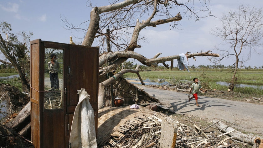 Young Burmese boy runs past house destroyed by Cyclone Nargis