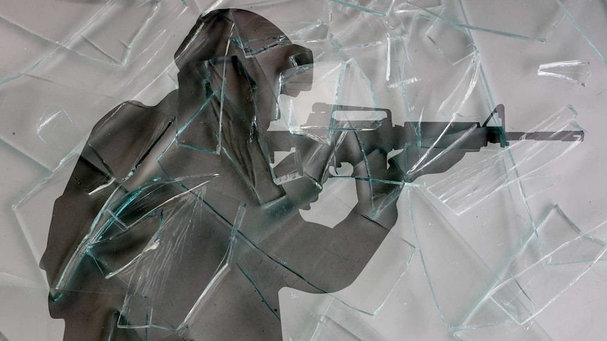 soldier holding a machine gun on the background of broken glass