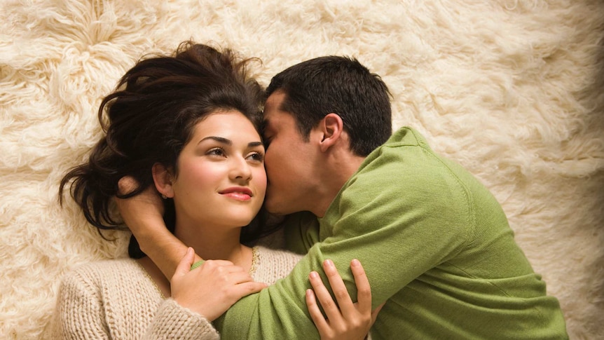 A young couple cuddling on a white rug