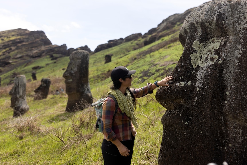 A woman touching a charred Moai statute