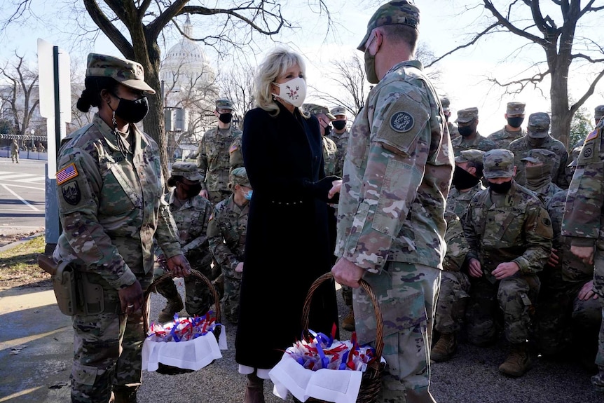Jill Biden shakes the hand of a guardsmen in front of other national guardsmen outside near the US Capitol in Washington DC