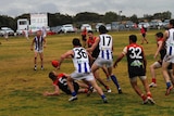 Men playing AFL on a country oval