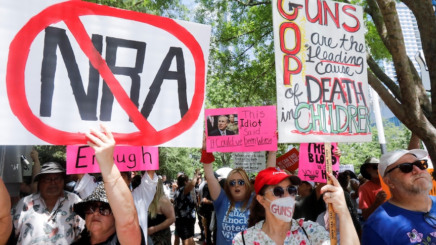 Protestors hold signs with NRA crossed out