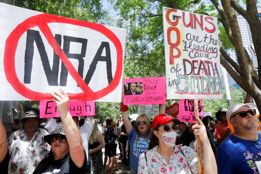 Protestors hold signs with NRA crossed out