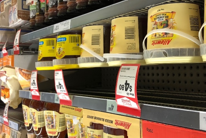 Allowrie honey stacked on shelves in Woolworths, alongside Capilano honey.