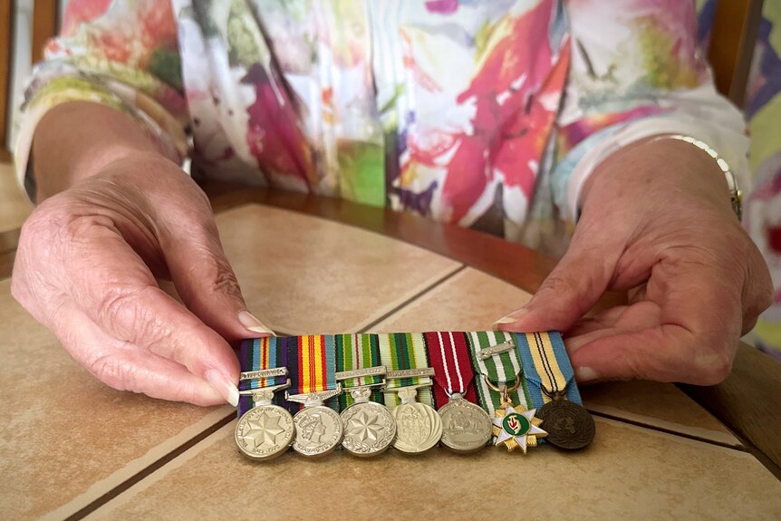 A woman's hands holding seven war medals