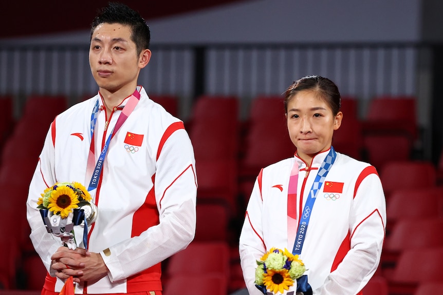 Xu Xin y Liu Shiwen de China parecen abatidos con sus medallas de plata en el podio