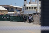 Detectives in a harbour with crime scene tape