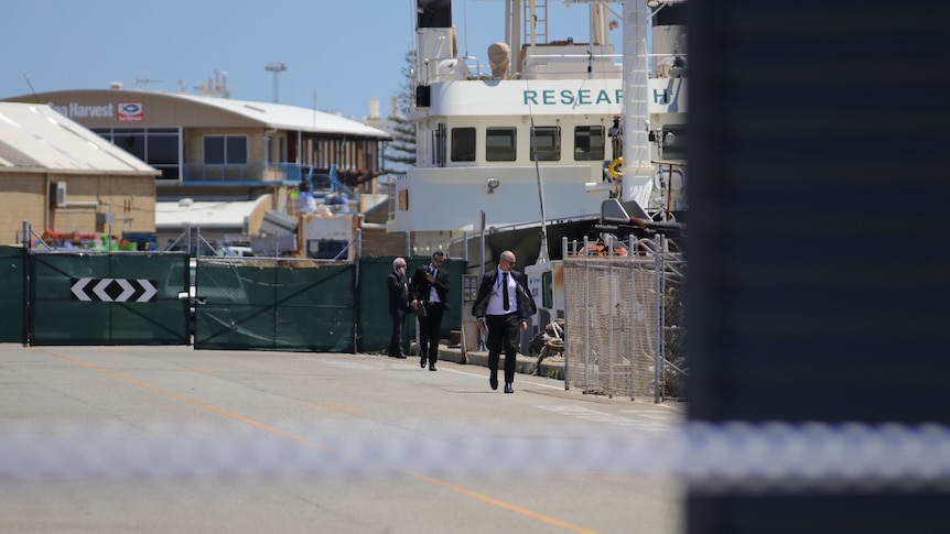 Detectives in a harbour with crime scene tape
