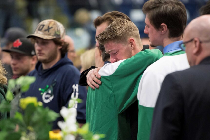 Mourners comfort each other during a vigil at the Elgar Petersen Arena