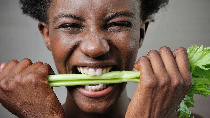 Smiling woman biting celery