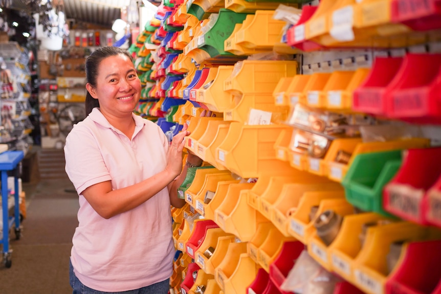 A Filipino woman standing alongside a rows of colourful plastic shelves.