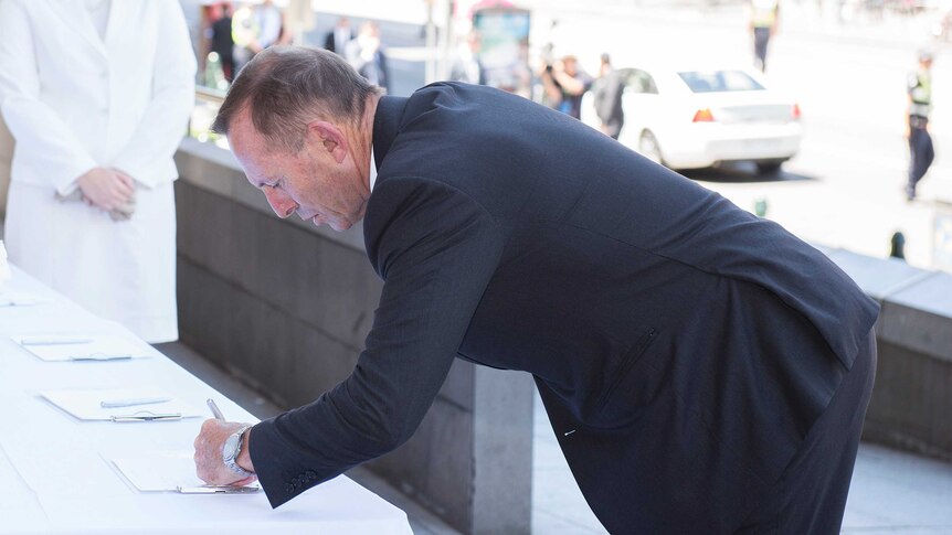 Former prime minister Tony Abbott signs the condolence book on arrival for the state funeral service for Ron Walker.