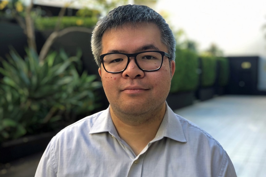 A man wears glasses and a collared shirt.