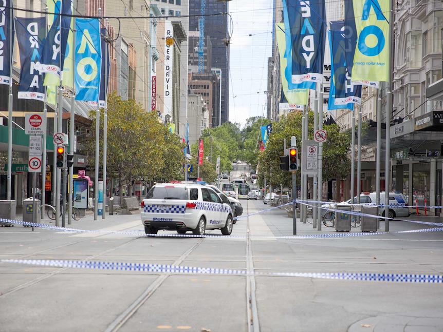 Bourke Street empty aside from trams and police cars.
