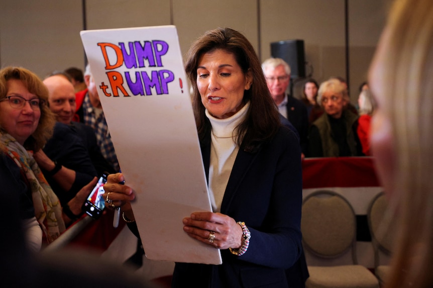 Nikki Haley holds a placard that says Dump Trump at a rally