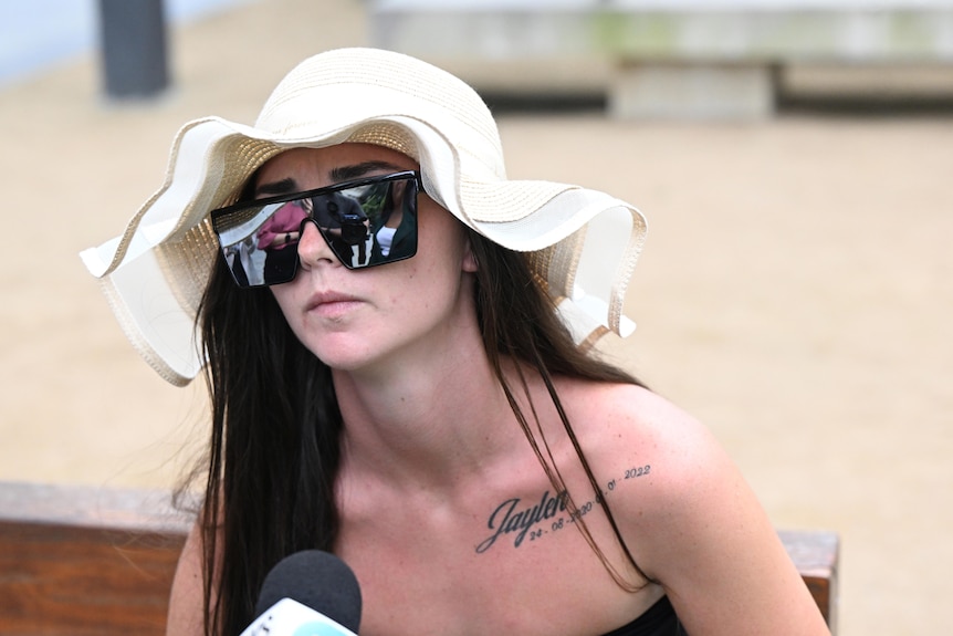  woman in a white sun hat talks to the press