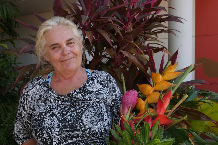 Female flower farmer holding native flowers, smiling at camera.