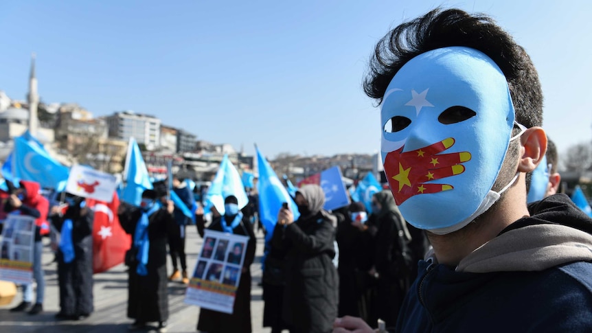 A man wearing a mask with the East Turkistan and Chinese flags