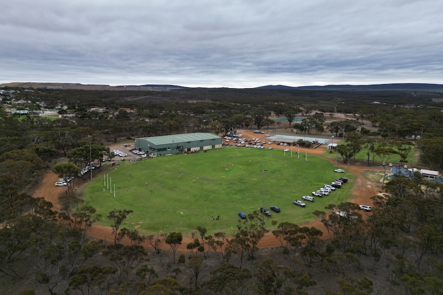 View from above of a football oval with cars parked around the edge
