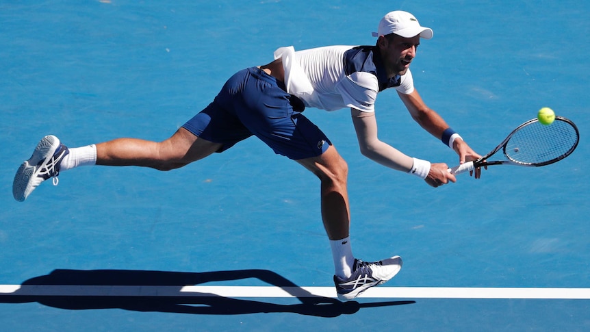 Novak Djokovic stretches to make a backhand return at the baseline against Gael Monfils at the Australian Open.