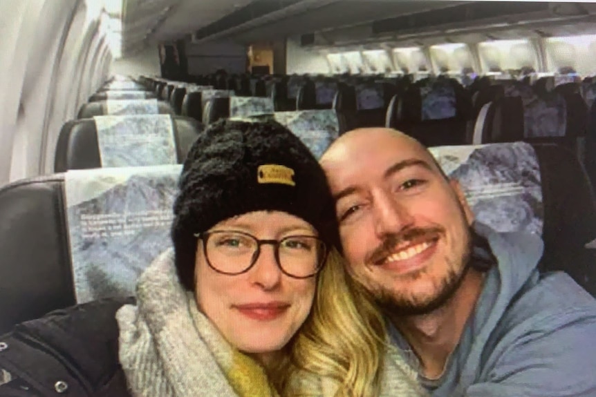 A woman and man take a selfie aboard a near-empty plane