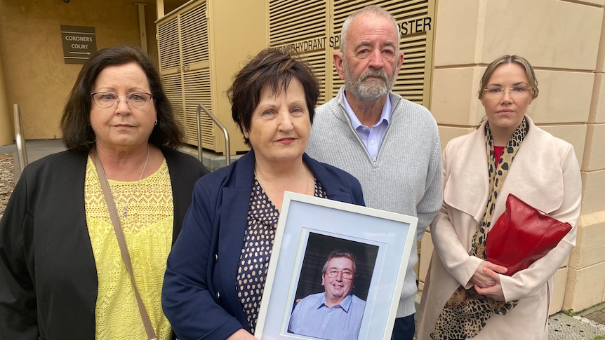 A family of four stand outside court holding a framed photo of their loved one