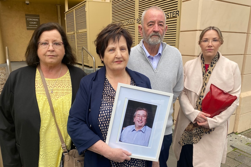 A family of four stand outside court holding a framed photo of their loved one