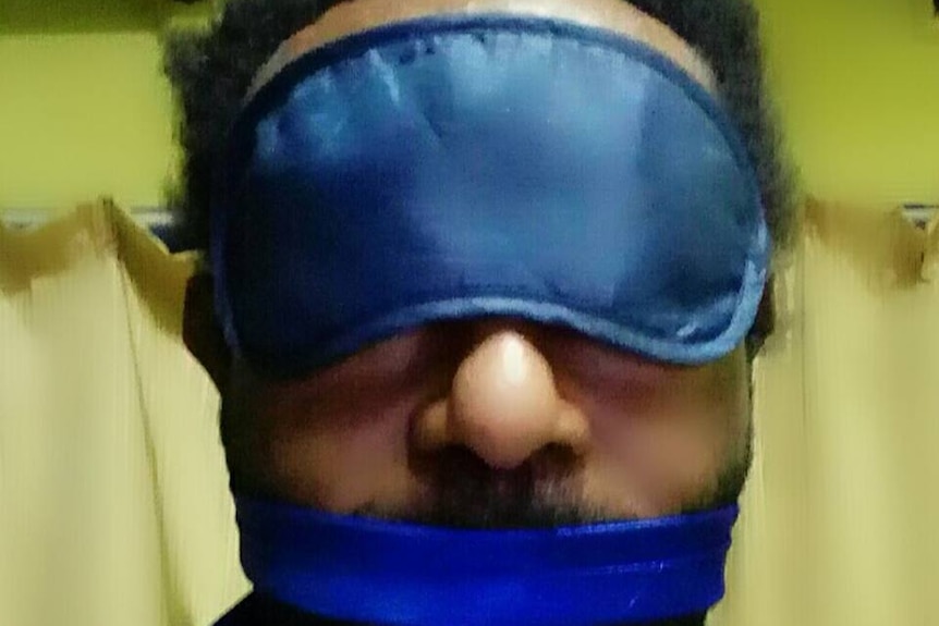 A headshot of blogger Martyn Namorong wearing an eye mask and mouth gag