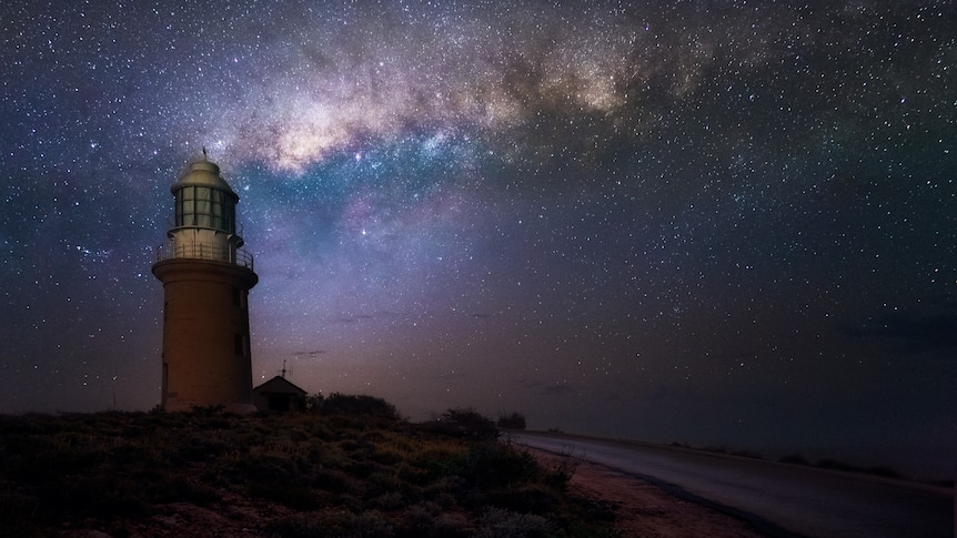 A night sky and lighthouse. The milky way is visible behind the lighthouse, with many stars in view.