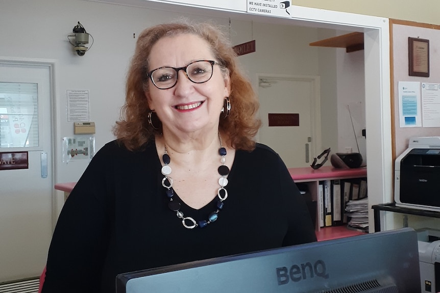 Lucina Wilk sits at a desk under a medical centre sign