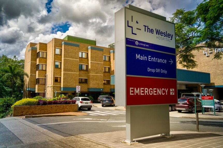 An entryway sign to The Wesley Hospital, with the building in the background.