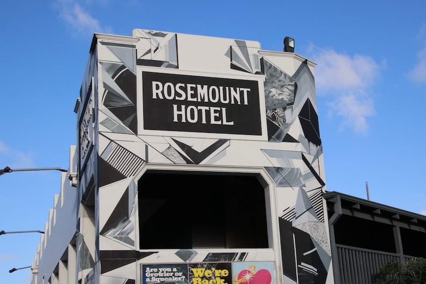 The Rosemount Hotel sign on the building in front of a blue sky.
