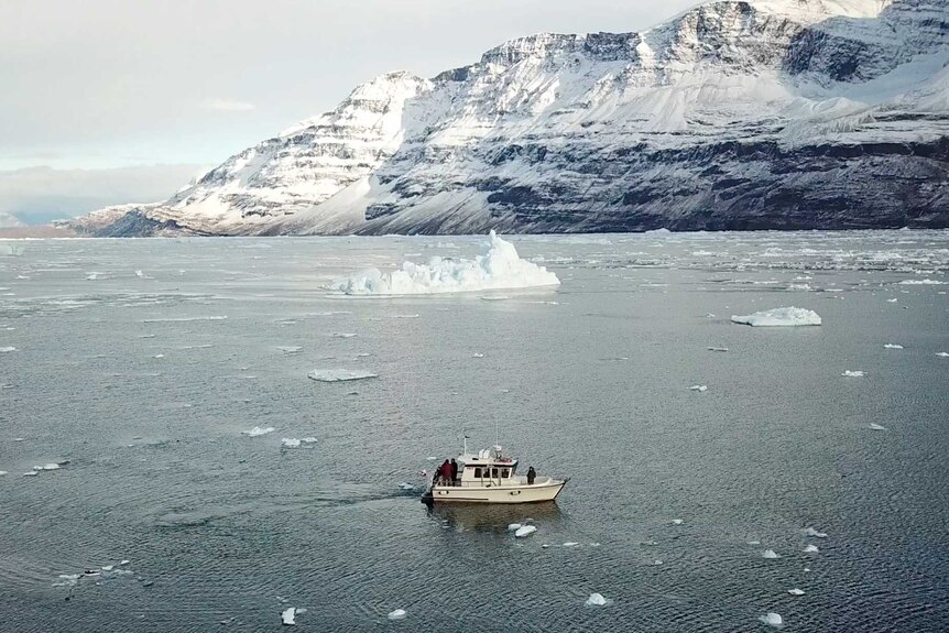 A boat travels through icy waters with glacier in background
