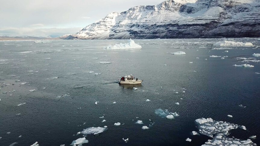 A boat travels through icy waters with glacier in background