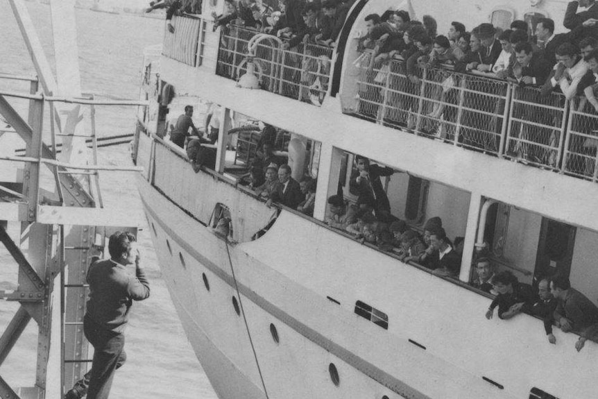 a black and white photo of a boat full of people looking onto a harbour