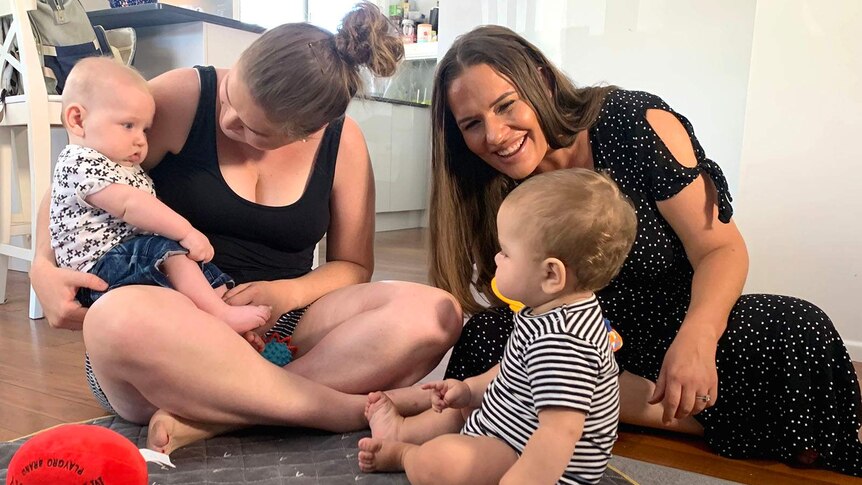 Two mothers playing on the floor with their babies